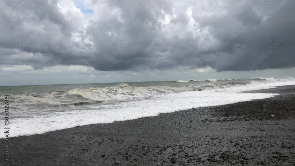 Storm at sea, storm warning on the coast. Thunderclouds and big sea waves during a storm. Big waves of a storm in Georgia on the Black Sea crashes ashore. Storm at sea, storm warning on the coast. Thunderclouds and big sea waves during a storm. Big waves of a storm in Georgia on the Black Sea crashes ashore.
