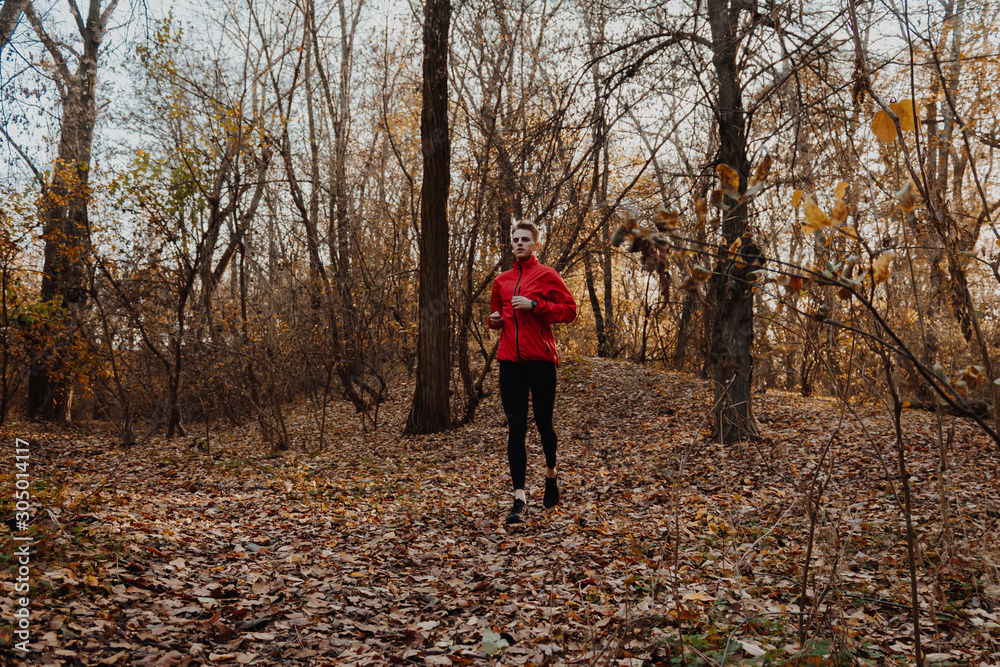 A guy in a red windbreaker runs in the autumn forest. A guy in a red windbreaker runs in the autumn forest.