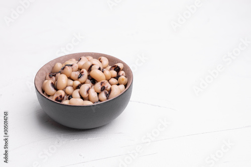 Cooked Fradinho beans in a black clay pot, isolated on a white background.
