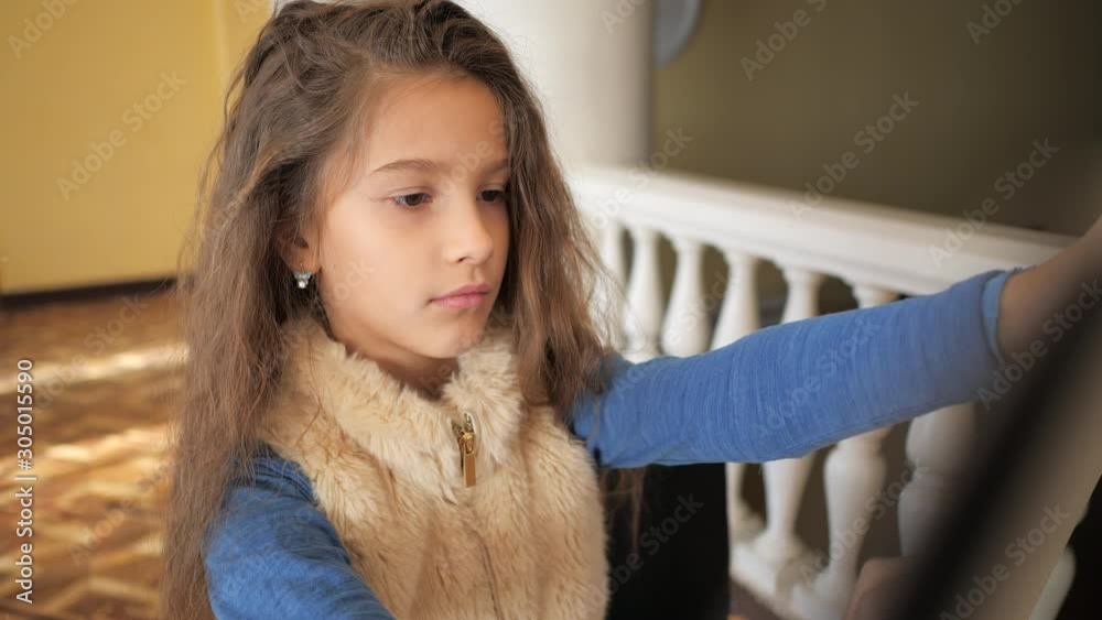 Handheld shot. A young girl with curly hair draws a drawing on an easel.