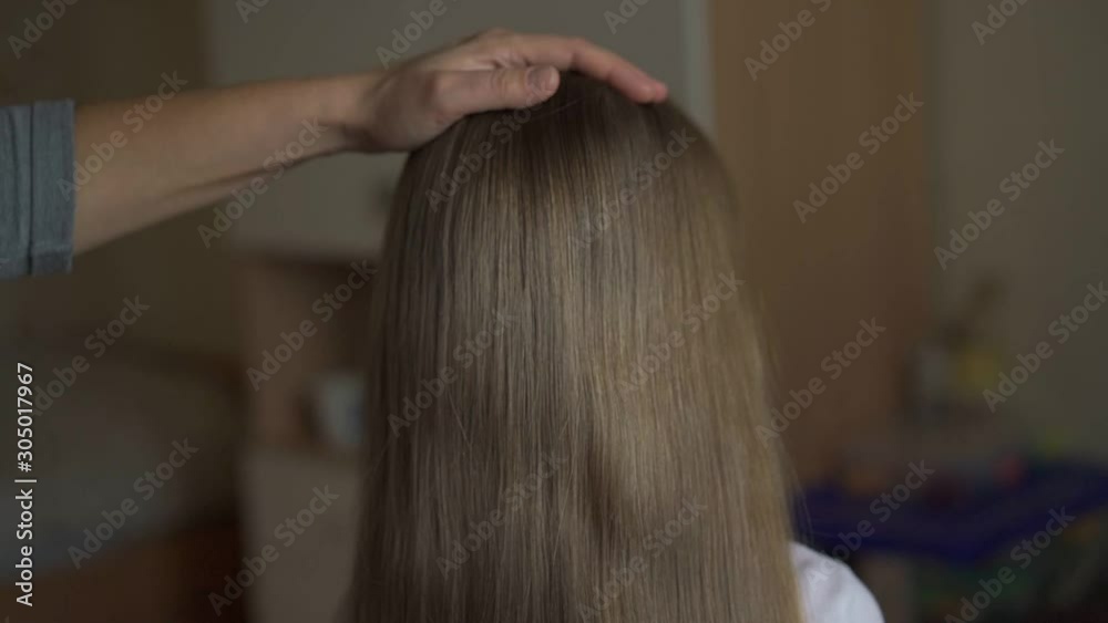 granny brushes accurately and gently granddaughter long blond straight hair with blue plastic hairbrush closeup slow motion granny brushes accurately and gently granddaughter long blond straight hair with blue plastic hairbrush closeup slow motion