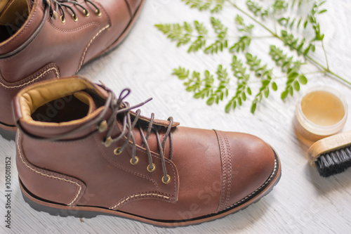 ฺBrown leather shoes with vintage camera on a wooden floor.Brown vintage leather boots aligned selective focus.Men leather shoes 