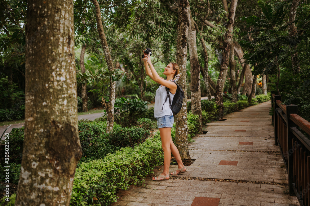 Traveler blonde backpacker woman  walking taking photos in tropical forest, Travel adventure nature in China, Tourist beautiful destination Asia, Summer holiday vacation trip, Copy space for banner