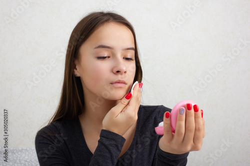 Health and beauty. Facial skin care. A young girl rubs her face with a tonic  nourishing lotion.