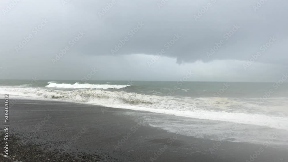 Storm at sea, storm warning on the coast. Thunderclouds and big sea waves during a storm. Big waves of a storm in Georgia on the Black Sea crashes ashore. Storm at sea, storm warning on the coast. Thunderclouds and big sea waves during a storm. Big waves of a storm in Georgia on the Black Sea crashes ashore.
