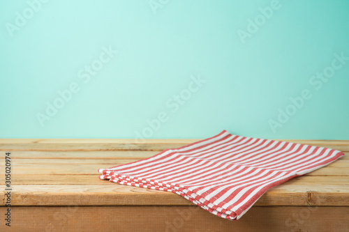 Empty wooden table with tablecloth over blue background