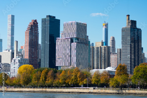 Shoreline of Roosevelt Island with the Midtown Manhattan Skyline in New York City with Colorful Trees during Autumn © James