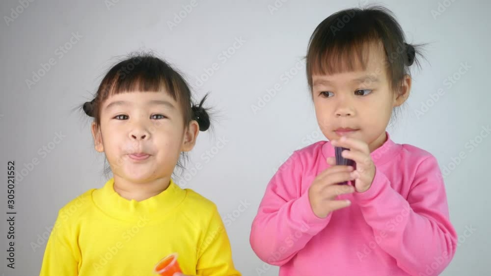 Portrait of a happy smiling brethren girls and enjoy eating gelatin dessert isolated on white background. Portrait of a happy smiling brethren girls and enjoy eating gelatin dessert isolated on white background.