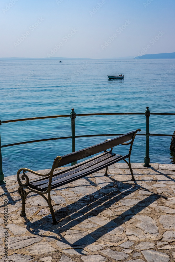 Wooden bench, Adriatic Sea and old boat in Town of Opatija on sunny summer day, Kvarner bay of Croatia