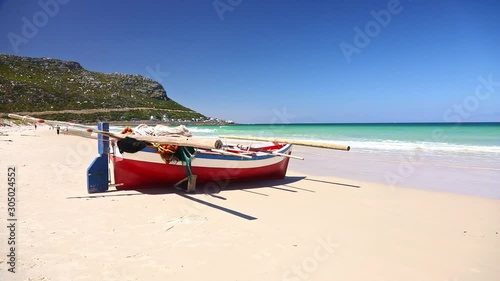 Small traditional type of fishing row boat resting on sand on Fish Hoek Beach, Cape Town