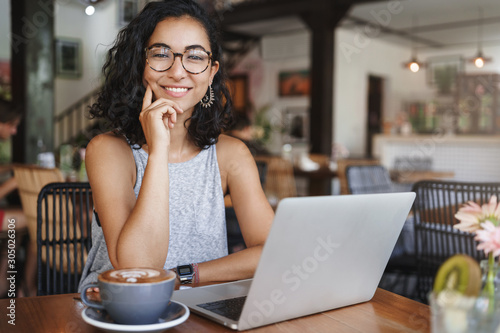 Business, corporate and recruitment concept. Cheerful good-looking female freelancer, young hipster girl student sit coworking place, cafe, smiling as using laptop and drink coffee, hr having meeting photo