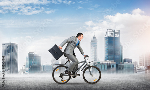 Man wearing business suit riding bicycle outdoor. © adam121