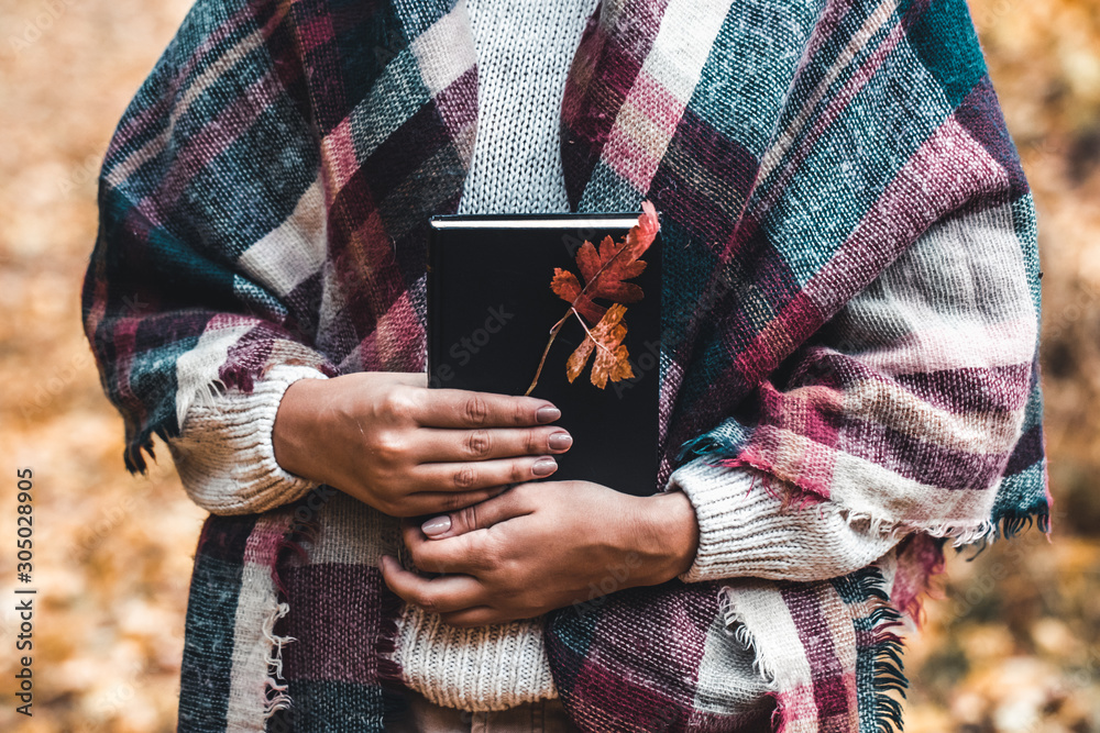 Fototapeta premium Woman holds a book in her hands, close-up, autumn