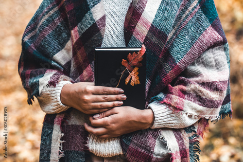 Woman holds a book in her hands, close-up, autumn