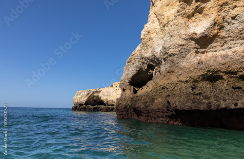 Beautiful landscape of Algarve  Portugal coast with sandstone cliffs  beach and ocean under cloudless blue sky 