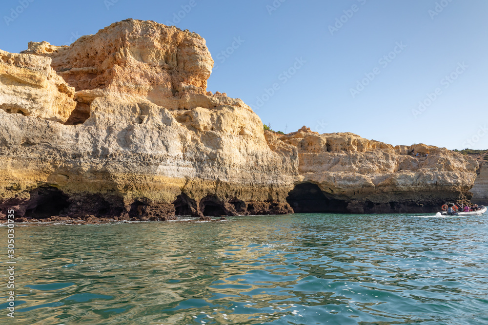 Beautiful landscape of Algarve, Portugal coast with sandstone cliffs, beach and ocean under cloudless blue sky	