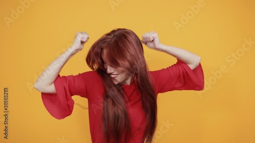 Beautiful red lady listening to good music and dancing. She is enjoying the music as it feels you feel better and forget your problems and it is good for your physical and mental health.
