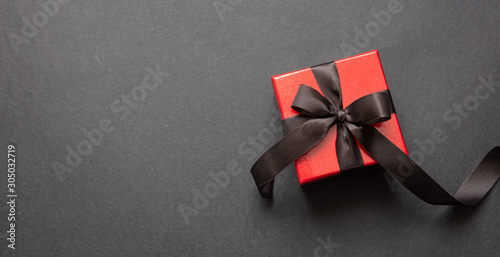 Gift box with black ribbon against black background, Black Friday concept.