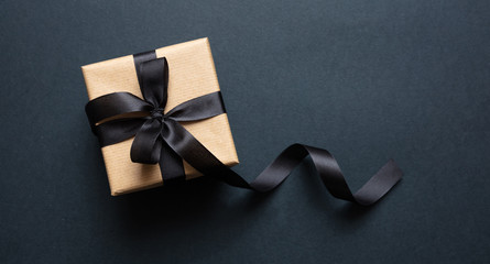 Gift box with black ribbon against black background, Black Friday concept.