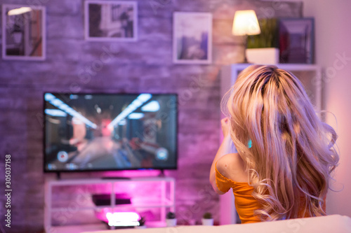 Back view of excited girl playing online shooter game