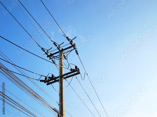 High and low voltage electrical wires on the pole On the background of a bright blue sky in the afternoon. With copy space