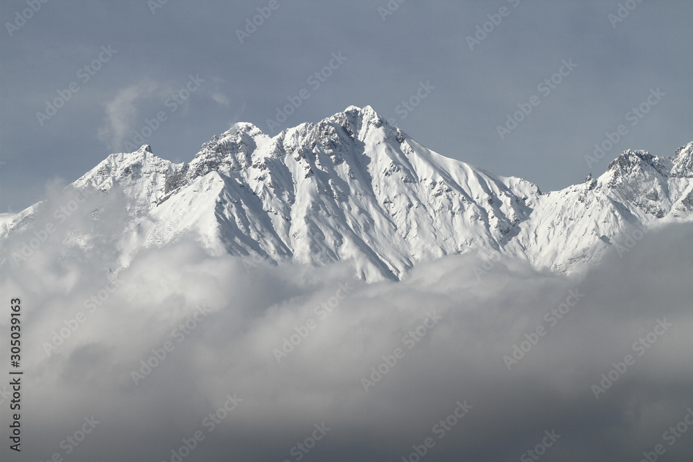 Blick von Innsbruck im Inntal in Tirol auf die Nordkette und die schneebedeckten Gipfel im Winter. Nebeldecke