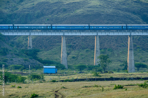 Passenger train crossing a viaduct at Shindawane near Pune India. photo