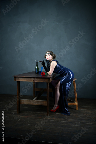 girl in a blue evening dress with a cigarette near the table