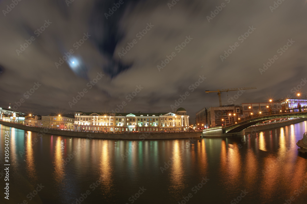 Moscow cityscape at autumn night. Bridge, reflections of city lighting on the water surface. Moskva river embankment. Long exposure photography