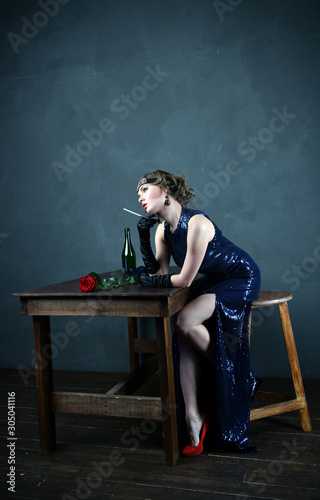 girl in a blue evening dress with a cigarette near the table