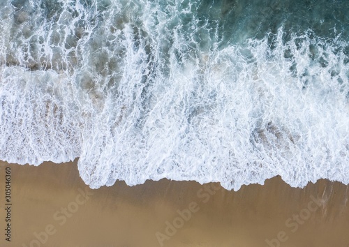 Aerial view of waves crashing at the beach.