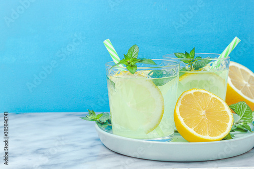 Lemon lemonade in mason jar glass ofwith lemons and straw on table background