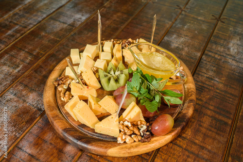 Cheese platter on a wooden plate on a large wooden table