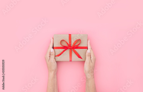 Female hands holding present box or gift box package in the craft paper