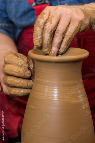 Professional male potter making ceramics on potters wheel in workshop, studio. Close up shot of potters hands. Handmade, art and handicraft concept