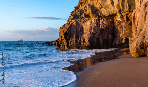 Beautiful Gran Canaria beach at sunset. Rocky shore  grotto and footprints in the sand.