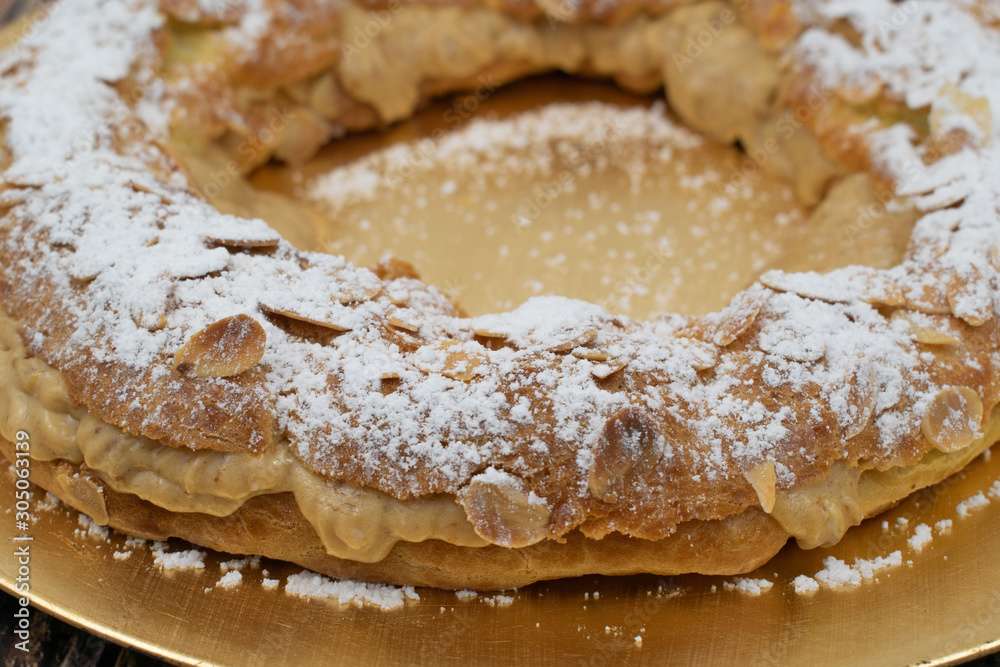 French dessert paris-brest whit sugar powder and almonds on the golden plate