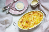 French dish Gratin Dauphinois in ceramic form on a light background. Rustic style.