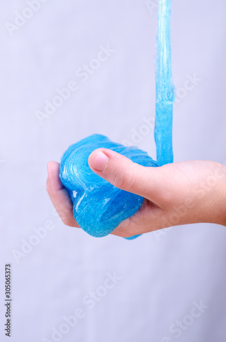 Child's hand holding bright glitter slime. Kid playing with slime, worldwide popular self made toy. photo