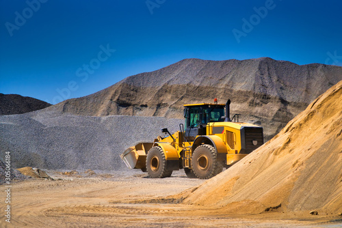 Maintenance of yellow excavator on a construction site against blue sky. repearing wheel loader at sandpit during earthmoving works photo