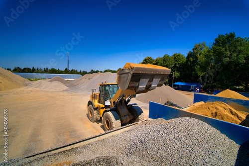 Sand quarry, excavating equipment, bulldozer with heap of sand and gravel in background. Selective focus.