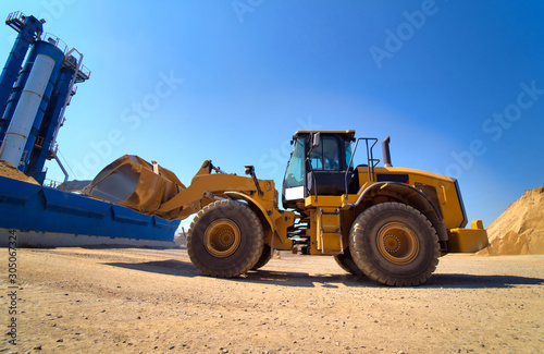 Maintenance of yellow excavator on a construction site against blue sky. wheel loader in sandheap background. Selective focus. photo