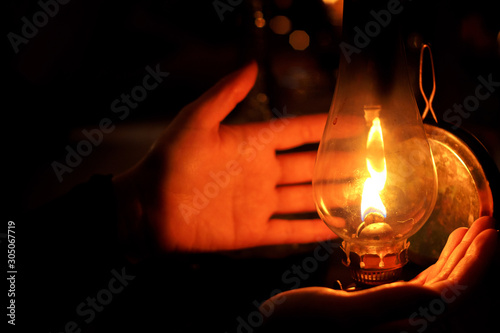 Hands next to oil lamp