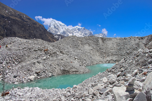 A beautiful lake of melted ice in the middle of Ngozumpa glacier strewn with stones. Cholatse and Taboche mountain peaks rises above it. Route to Everest base camp through Gokyo Lakes. photo