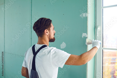 Schilderij op canvas Worker builder plasterer plastering a wall of drywall at a construction site ind
