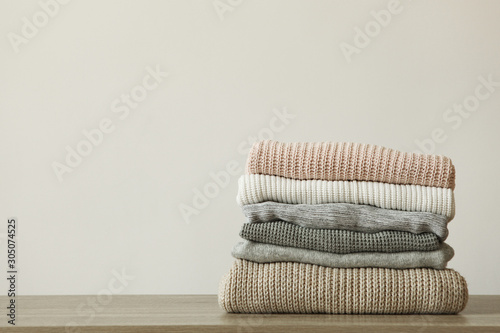 a stack of warm sweaters on the table on a colored background. © White bear studio 