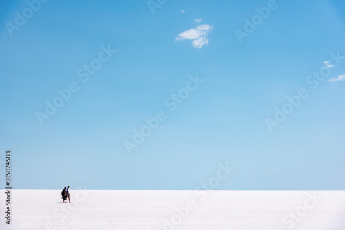 Shot of dry salt lake Tuz Golu with clear blue sky and unrecognizable tourists walking. photo
