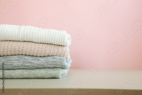 a stack of warm sweaters on the table on a colored background.