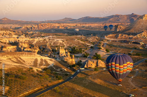 View from above to colorful hot air balloons flying over valleys and fields at early morning. Turkey, Cappadocia.