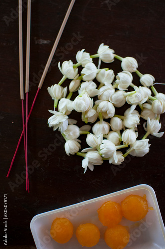 Fragrant jasmine blossom garland wrapped in circle on wooden table traditionally used as an offering to the ghosts and spirits in Thailand.